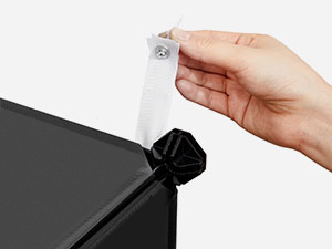 Tenez à la main une agrafe ou un fermoir blanc près d'un bord en tissu noir, pour démontrer la fixation ou le mécanisme de fixation