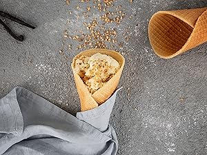 Cornet avec boule de glace et topping sur une table, vu du dessus