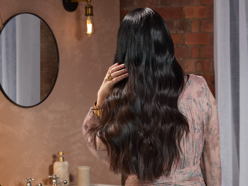 Séquence montrant une personne aux longs cheveux noirs effectuant un nettoyage du visage ou une routine de soins de la peau dans une salle de bain.