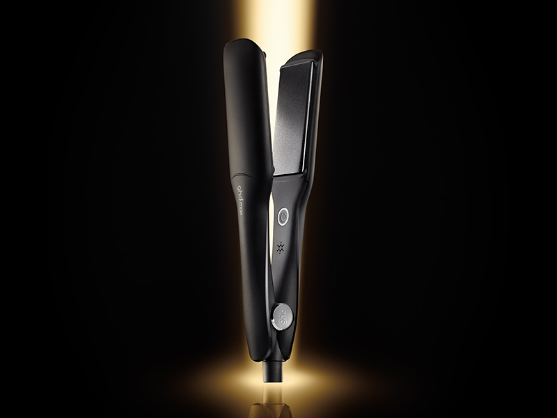 Outil de coiffure noir avec partie supérieure illuminée de façon spectaculaire sur fond sombre avec effet de lumière éclatante.