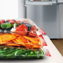 Légumes frais colorés disposés sur une planche à découper avec un récipient métallique en arrière-plan.