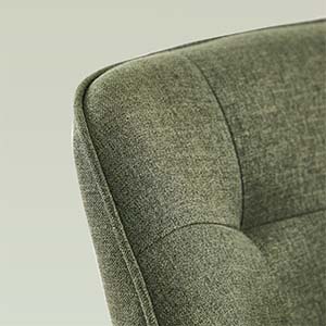 Gros plan d'un meuble rembourré texturé vert, montrant des bords incurvés et des détails capitonnés sur la surface