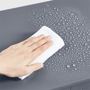 une personne nettoyant une table grise avec des gouttelettes d'eau