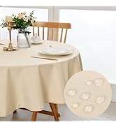 sur table à manger ronde. L'encart montre des gouttelettes d'eau perlant sur la surface du tissu. Set de table avec assiettes, fleurs dans un vase et bougeoir.