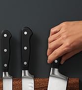 la main d'une personne tenant un couteau sur une planche de bois.