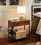 Table de chevet en bois avec structure en métal, avec tiroir et étagère inférieure. La lampe de table avec abat-jour blanc et base cylindrique se trouve au sommet, à côté de livres et d'un réveil