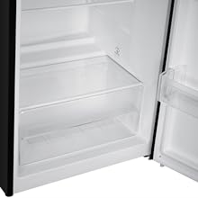 Vue intérieure d'un compartiment de réfrigérateur, montrant une étagère en verre transparent vide et une partie d'une porte ouverte.