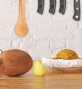 Scène de cuisine avec une cuillère en bois, des manches de couteau, de la noix de coco, du citron et du pain dans un panier sur une surface en bois sur fond de brique blanche.