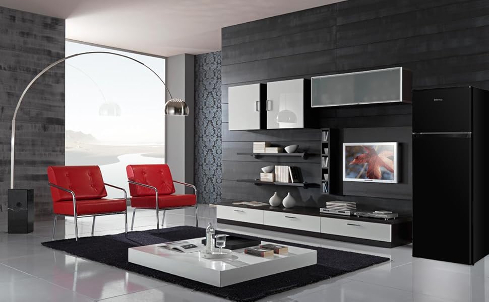 Salon moderne avec palette de couleurs noir et blanc. Elle comprend des fauteuils d'appoint rouges, un grand meuble de télévision, des étagères flottantes et une fenêtre cintrée avec vue sur la ville