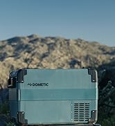 avec extérieur bleu-gris, évents visibles et coins renforcés, positionné à l'extérieur avec un paysage montagneux en arrière-plan