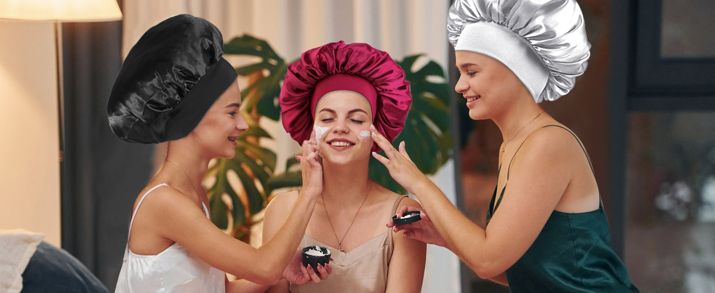 Trois personnes portant des bonnets de douche et des bonnets à cheveux de différentes couleurs (bordeaux, blanc et noir) lors d'une séance de spa ou de beauté