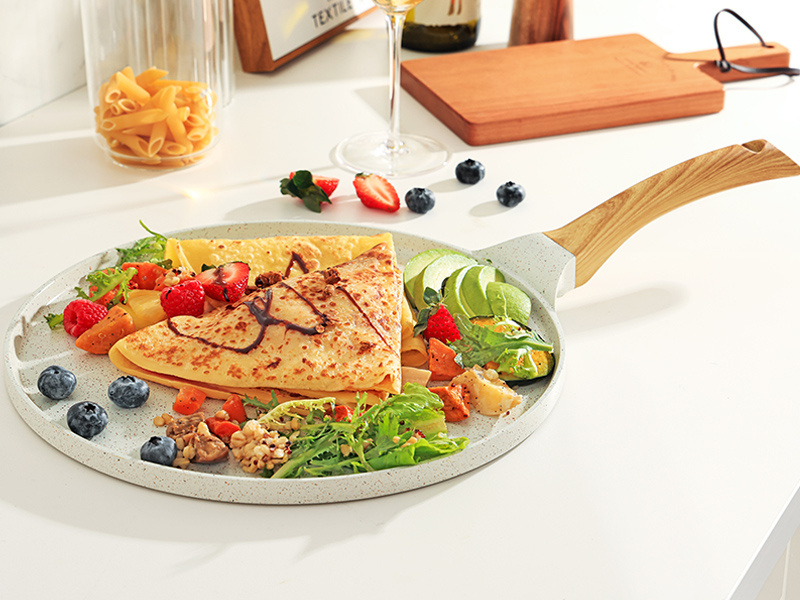 Crêpes ou crêpes fines dans une assiette de service ronde avec des fruits frais, des quartiers de lime et une garniture de salade. Assiette de service à manche en bois