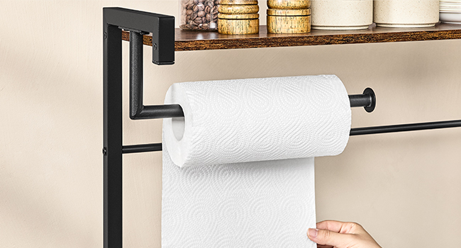 Porte-essuie-tout en métal noir avec tige horizontale et support vertical. Fixé à une étagère en bois. Essuie-tout blanc monté sur rouleau, avec feuille à tirer à la main.