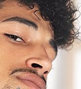 Gros plan du visage d'une personne, montrant une partie du nez, de la bouche et des cheveux bouclés sur fond blanc