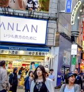 Scène de rue urbaine avec une signalisation en vitrine et des piétons passant devant des établissements commerciaux