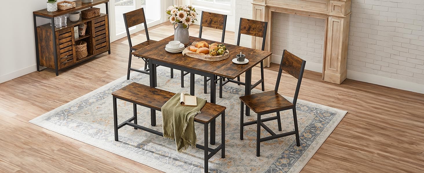 avec table en bois, quatre chaises et un banc. Buffet inclus. Situé sur un sol en bois clair avec un tapis blanc en dessous.