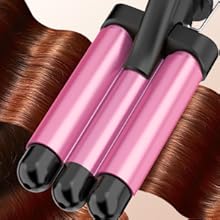 Trois outils de coiffure cylindriques roses aux extrémités noires, placés sur une mèche de cheveux bruns, suggérant une fonction de frisage ou de lissage des cheveux