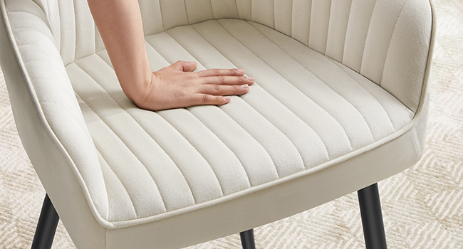 Gros plan d'un siège de chaise de salle à manger rembourré de couleur crème avec motif capitonné à canaux verticaux, montrant un tissu texturé