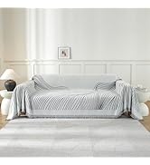 Canapé à rayures blanches dans une pièce minimaliste lumineuse avec des murs blancs et un décor subtil. Plusieurs vues montrant toute la longueur du canapé contemporain.