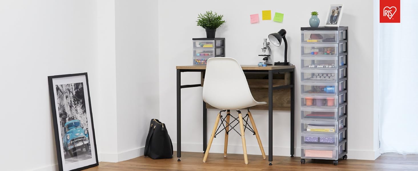 La vue intérieure de la pièce montre du parquet, des murs blancs ornés d'œuvres d'art encadrées et un mobilier moderne, notamment des chaises et une table de style Eames.