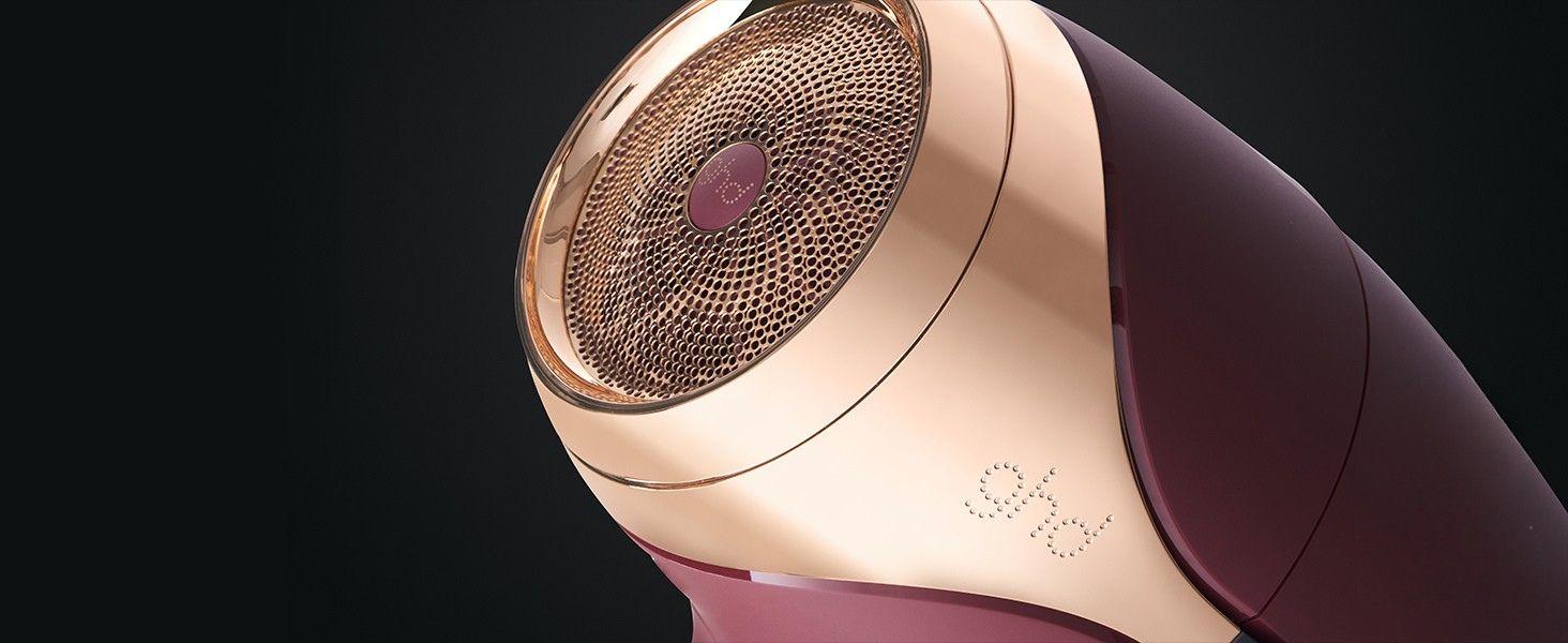 Gros plan d'un rasoir électrique ou d'un appareil de toilettage de couleur or rose avec une tête coupante à mailles circulaires sur fond sombre.