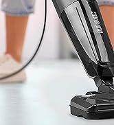 une personne debout à côté d'un aspirateur.