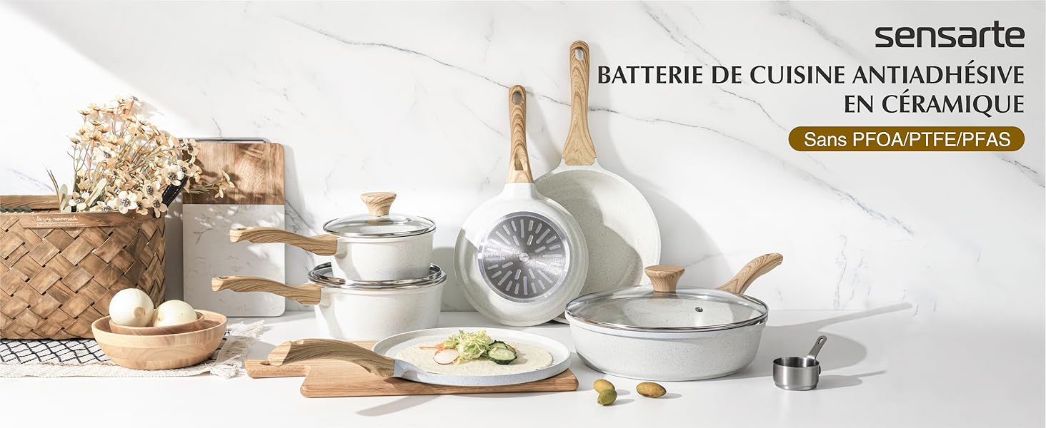 Ensemble d'ustensiles de cuisine en céramique blanche avec poignées en bois, comprenant des casseroles, des poêles et des ustensiles, disposés sur une surface blanche avec des éléments décoratifs