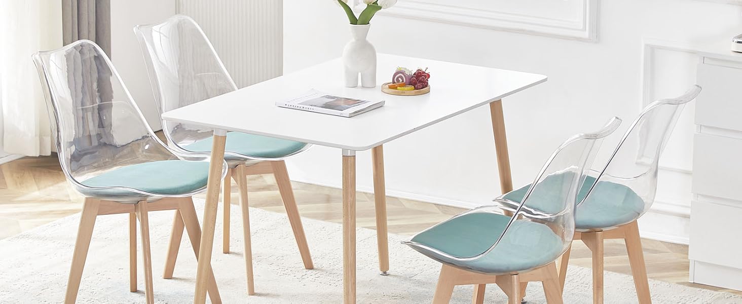avec table rectangulaire blanche et quatre chaises. Les chaises ont des sièges bleu clair et des pieds en bois. Cette chambre lumineuse est dotée d'une fenêtre et d'une décoration murale.