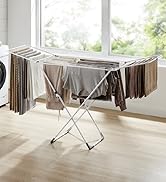 Séchoir à linge pliable à plusieurs bras pour suspendre le linge, installé près d'une fenêtre dans une buanderie.