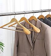 Tringle à vêtements avec divers vêtements sur des cintres en bois, y compris des costumes et des chemises de couleurs neutres