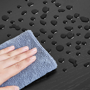 Gros plan d'une main essuyant une surface foncée et perforée avec un chiffon en microfibre bleu, montrant le nettoyage