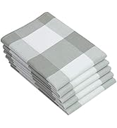 Pile de serviettes pliées avec un grand motif à carreaux gris et blanc. Les serviettes semblent être faites d'un tissu et sont soigneusement pressées et