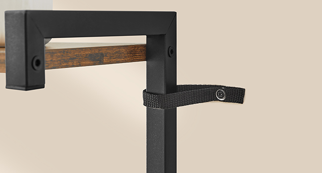 Gros plan d'une patère murale en métal noir avec une barre décorative en bois. Dispose d'une sangle noire ajustable avec fermeture à bouton-pression.