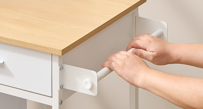 Séquence rapprochée montrant des mains en train d'installer des éléments de quincaillerie de meubles blancs sur une surface en bois, montrant les étapes d'assemblage.