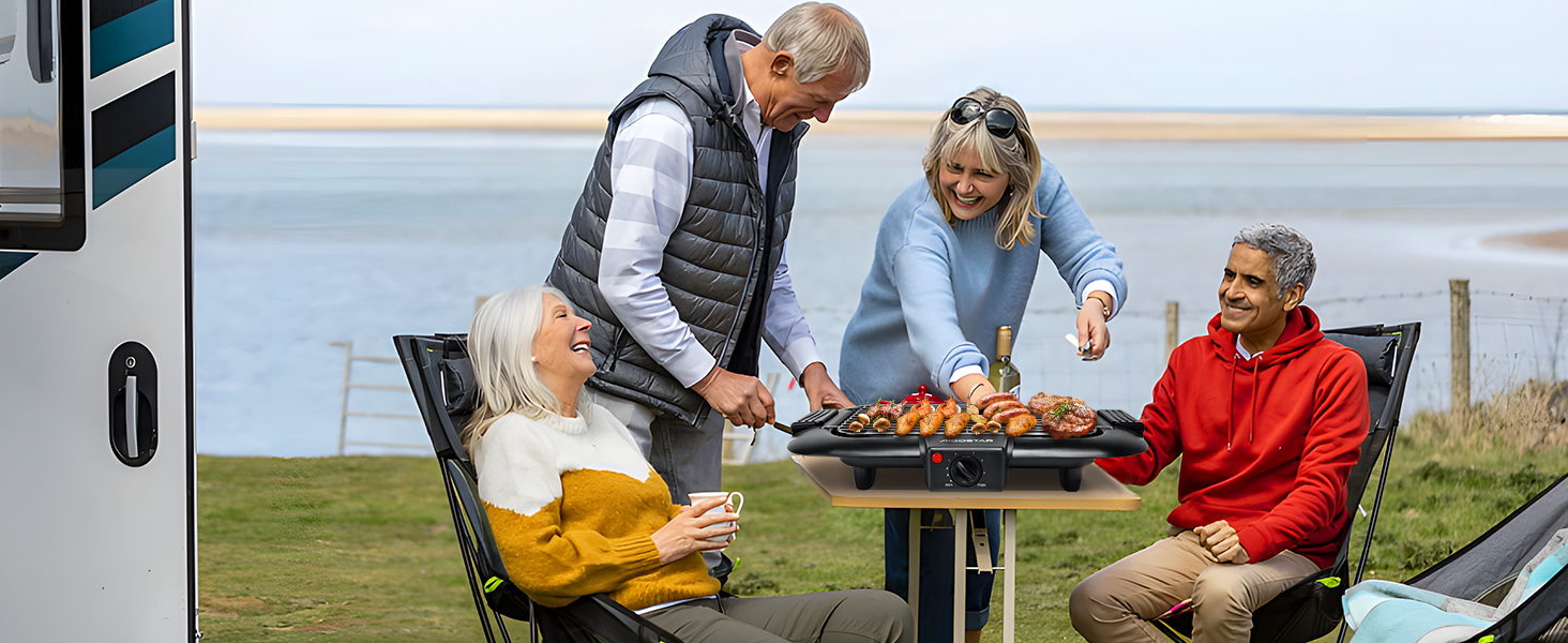 Cuisiner et manger en groupe à une table portable près d'un camping-car au bord de la mer. Les gens font des grillades et socialisent