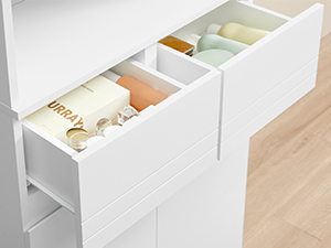 Tiroir de rangement blanc à compartiments multiples présentant des espaces de rangement organisés contenant des articles pliés aux couleurs pastel.