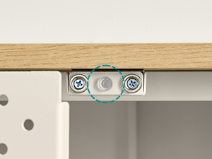 Gros plan d'un support de montage ou d'un assemblage de quincaillerie montrant des composants métalliques percés de trous de vis contre une surface en bois clair