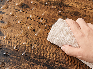 Utilisez à la main une éponge ou un chiffon texturé de couleur claire pour nettoyer une surface en bois présentant des grains visibles et de la sciure éparpillée