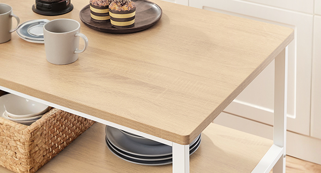 Table ou bureau en bois clair avec structure en métal blanc. Tasses à café et assiettes visibles sur la surface supérieure, panier de rangement en dessous.