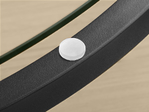 Gros plan d'un petit point ou bouton adhésif circulaire blanc monté sur une surface noire sur fond beige