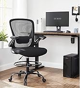 Fauteuil de dessin noir à dossier maillé avec hauteur réglable, accoudoirs et repose-pieds, positionné sur un bureau en bois avec écran