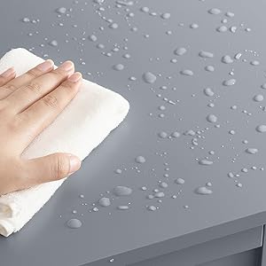 Essuyer à la main une surface résistante à l'eau avec un chiffon blanc. De nombreuses gouttelettes d'eau visibles sur la surface grise, démontrant ses propriétés hydrophobes