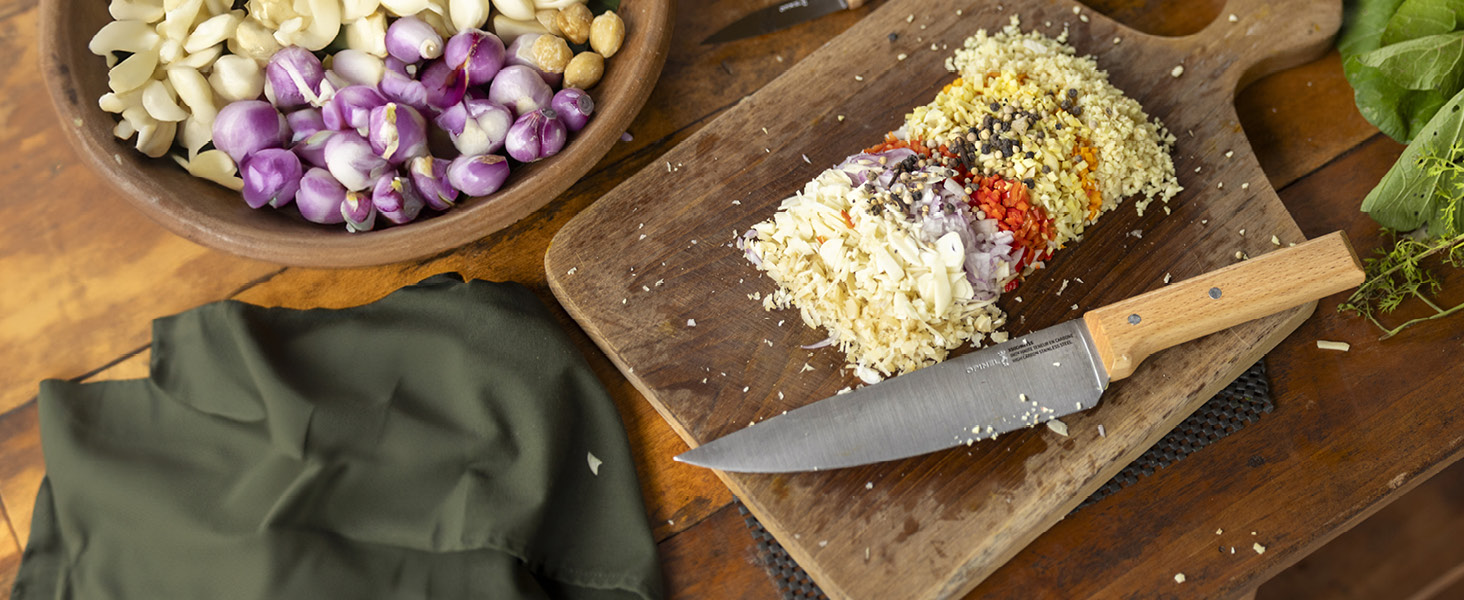 Gros plan de la préparation de rouleaux de sushi sur une planche à découper en bois avec des ingrédients hachés et des oignons violets dans un bol à proximité