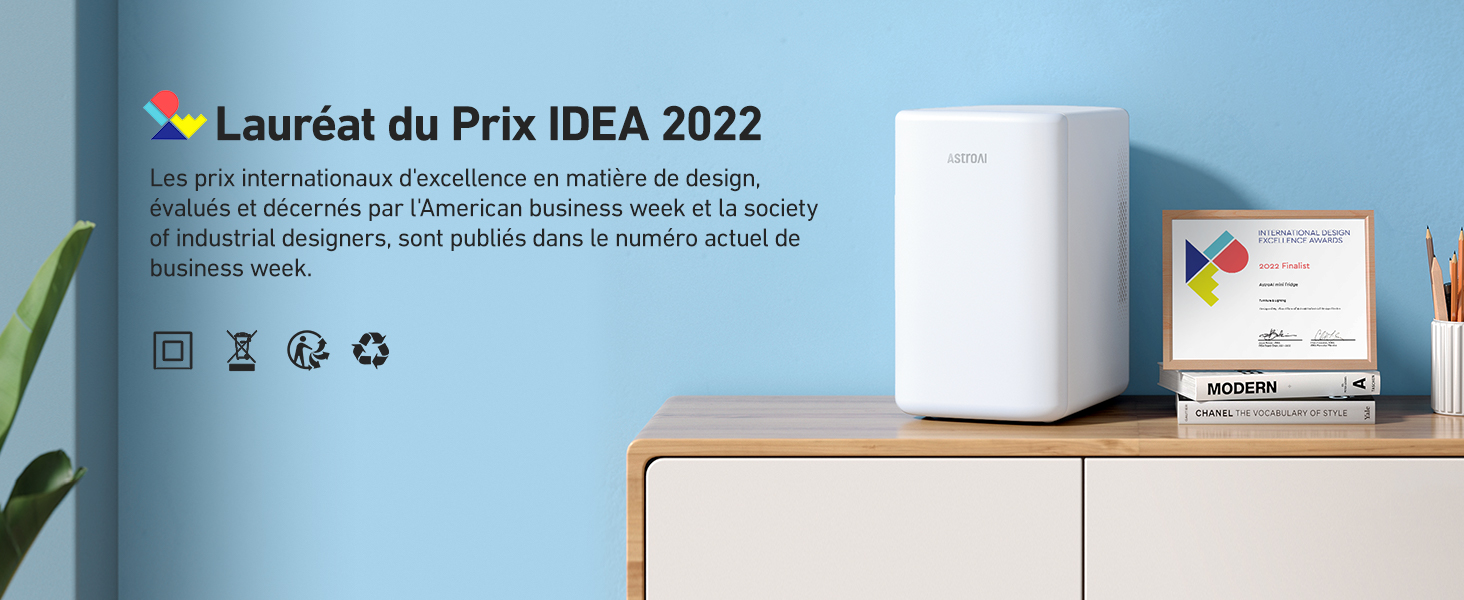 Appareil électronique compact blanc sur une surface en bois, avec les informations sur les récompenses et les icônes affichées ci-dessus.