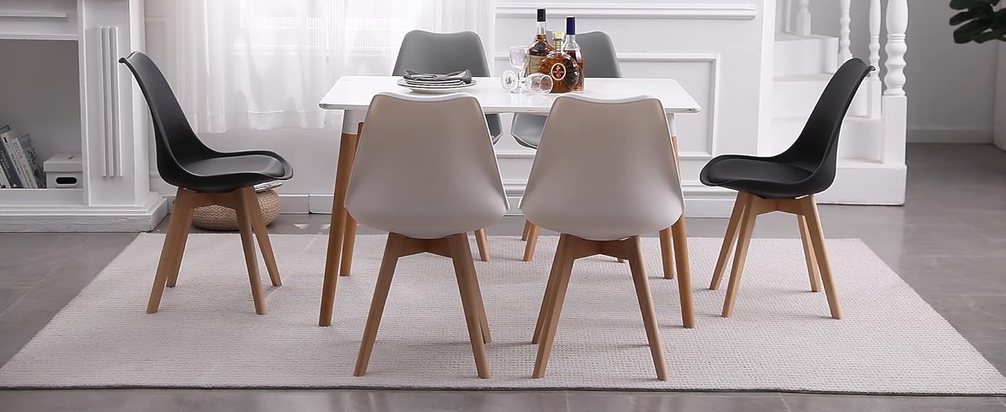 avec table rectangulaire blanche et six chaises - quatre blanches, deux noires. Situé dans une pièce lumineuse et minimaliste avec des éléments décoratifs.