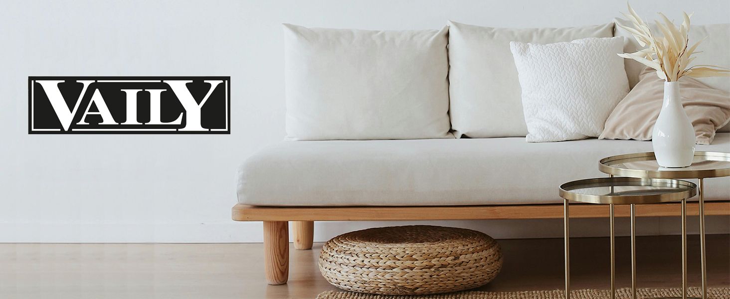 Configuration de salon minimaliste avec canapé blanc, base en bois, pouf de sol rond tissé et table d'appoint en verre contre un mur blanc