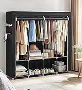 Grande armoire en tissu noir à façade ouverte, présentant des vêtements suspendus, des étagères avec des articles pliés et des chaussures sur le panier inférieur.