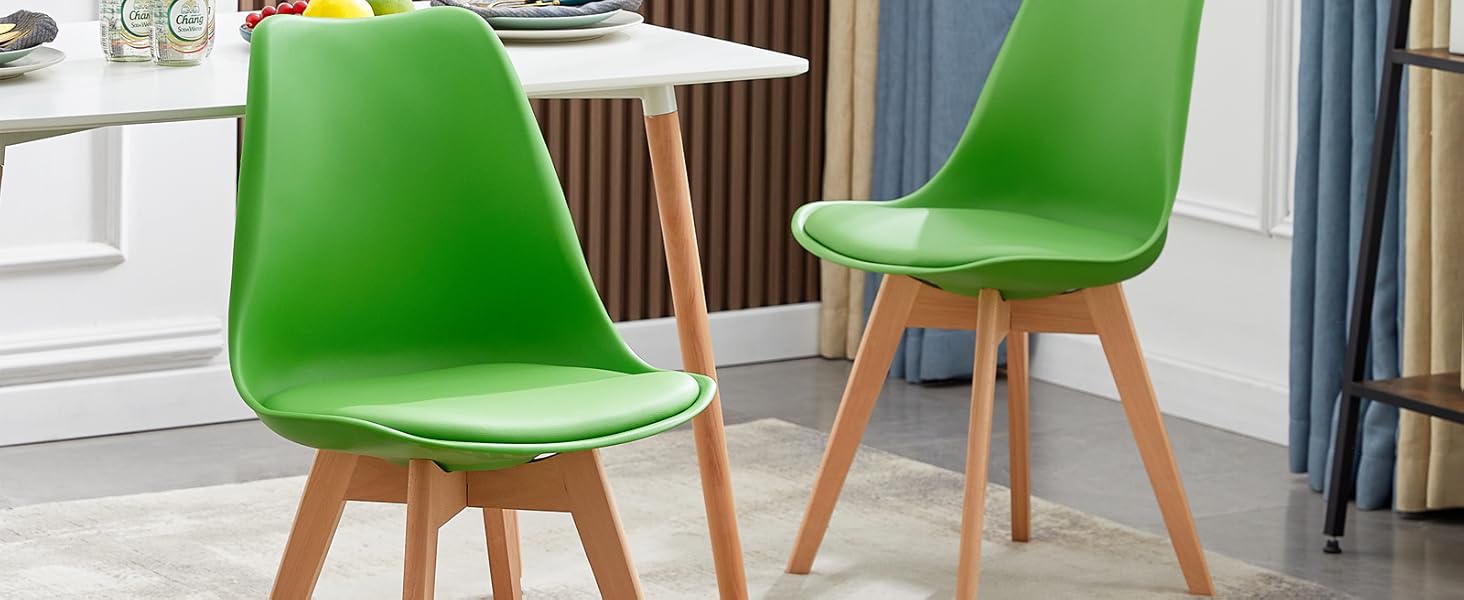 Deux chaises de salle à manger modernes vert vif avec des sièges rembourrés et des pieds en bois, placées près d'une petite table blanche dans un cadre familial