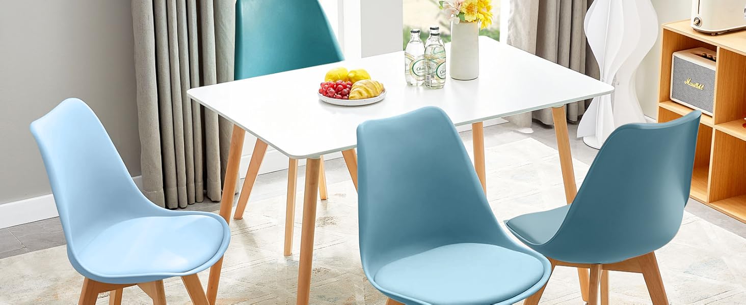 Ensemble de salle à manger moderne avec table rectangulaire blanche et quatre chaises bleu clair avec pieds en bois. Cette chambre possède de grandes fenêtres et des éléments décoratifs.