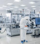 Laboratoire ou usine de fabrication propre et stérile avec des équipements automatisés, des machines et des accents bleus sous éclairage fluorescent.